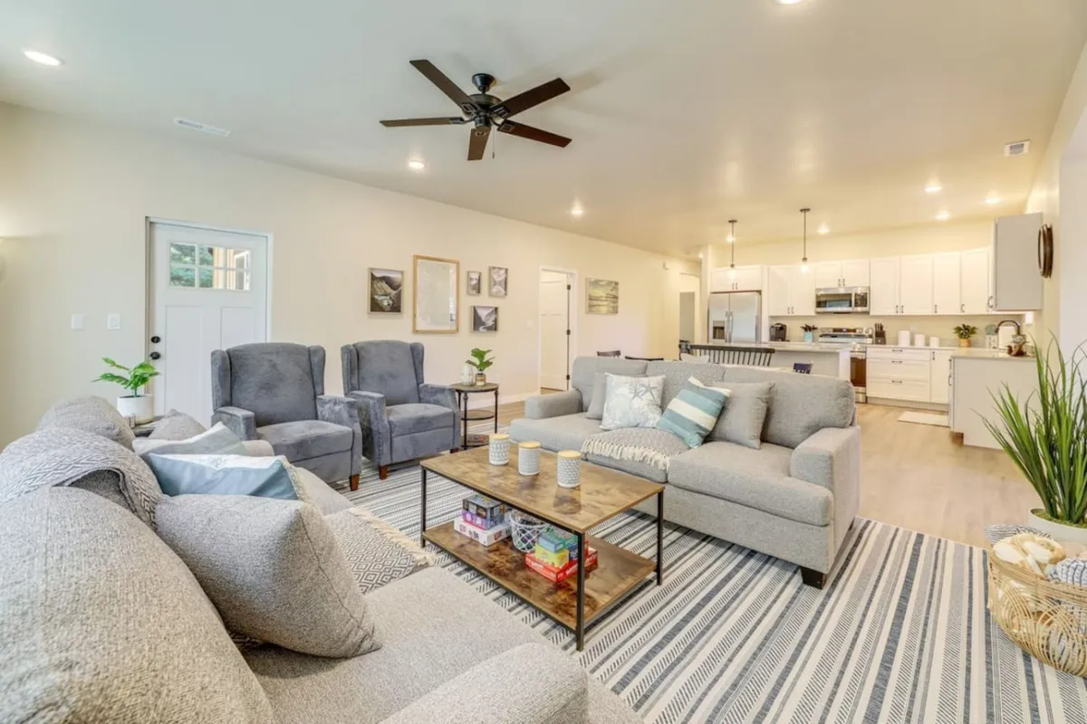 A bright, cozy living room with comfortable seating and a coffee table, seamlessly opening into an adjacent kitchen area. The open-plan design encourages group gatherings, while tasteful decor creates a homey environment perfect for both relaxation and socializing.