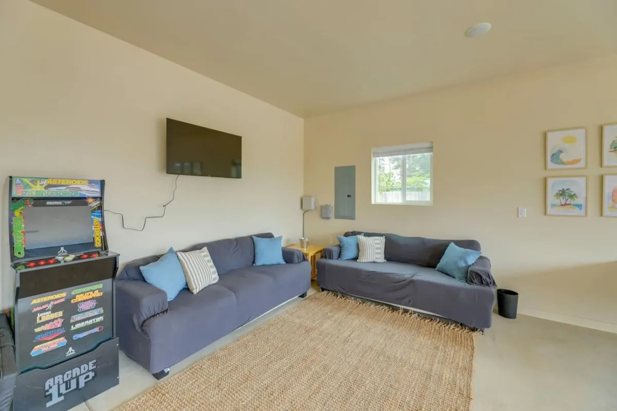 Featuring a classic arcade game, cozy sofas, colorful wall art, and a television, this image radiates a playful energy and retro vibe. The layout encourages both solo gaming and group gatherings, perfect for all ages.