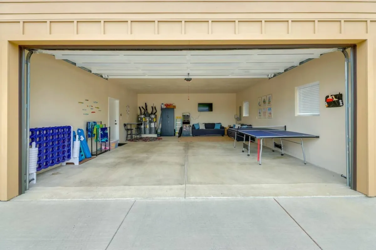A ping pong table is the main focal point, complemented by a sofa for comfortable spectating and relaxation. Decorative wall art and a storage area add personality and a welcoming, family-friendly touch to the space.